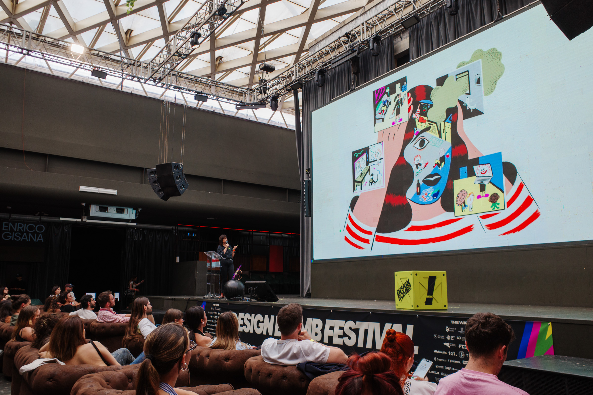 Sarah Mazzetti sul palco con lo schermo che mostra una sua illustrazione colorata